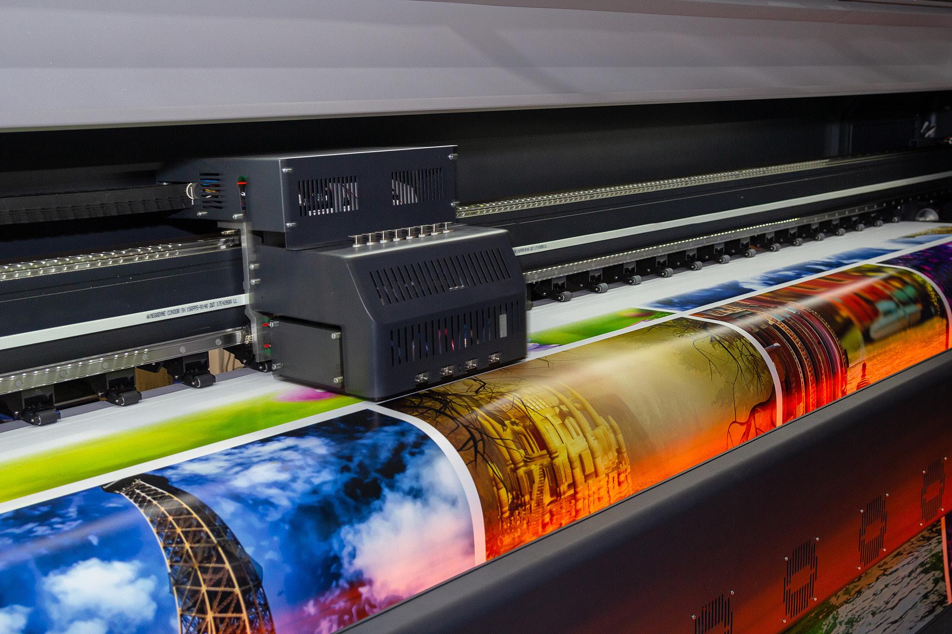 A wide-format printer producing high-resolution, full-color graphics as printed material moves through the machine.